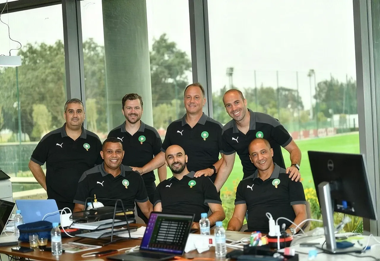 Teammates in matching shirts gathered around laptops