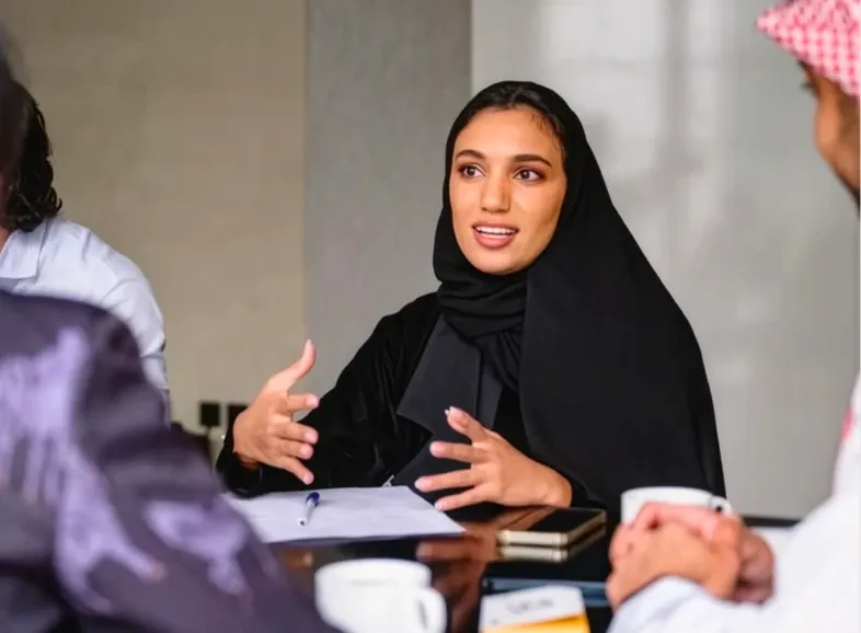 A woman explaining an idea across a meeting table